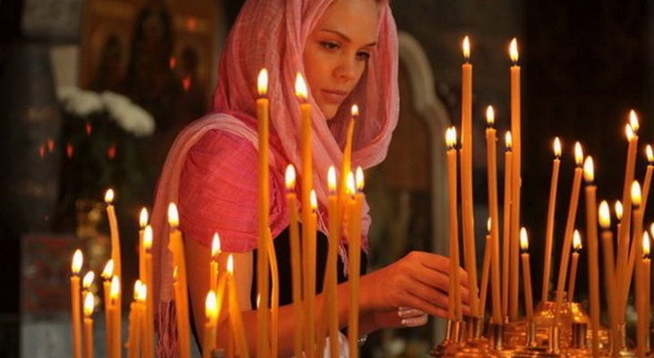 Девушка ставит свечу